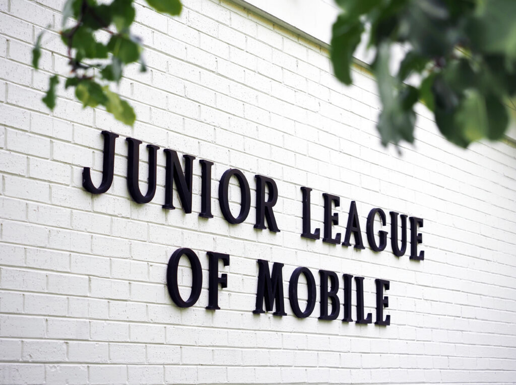 Junior League of Mobile sign on white brick wall